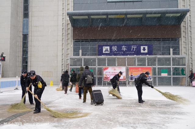 1月27日，革命圣地延安飘起中雪，铁路民警在延安火车站进站口扫雪，避免旅客滑倒。